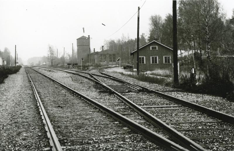 Raiteita, etualalla puinen rakennus, taaempana korkea torni.