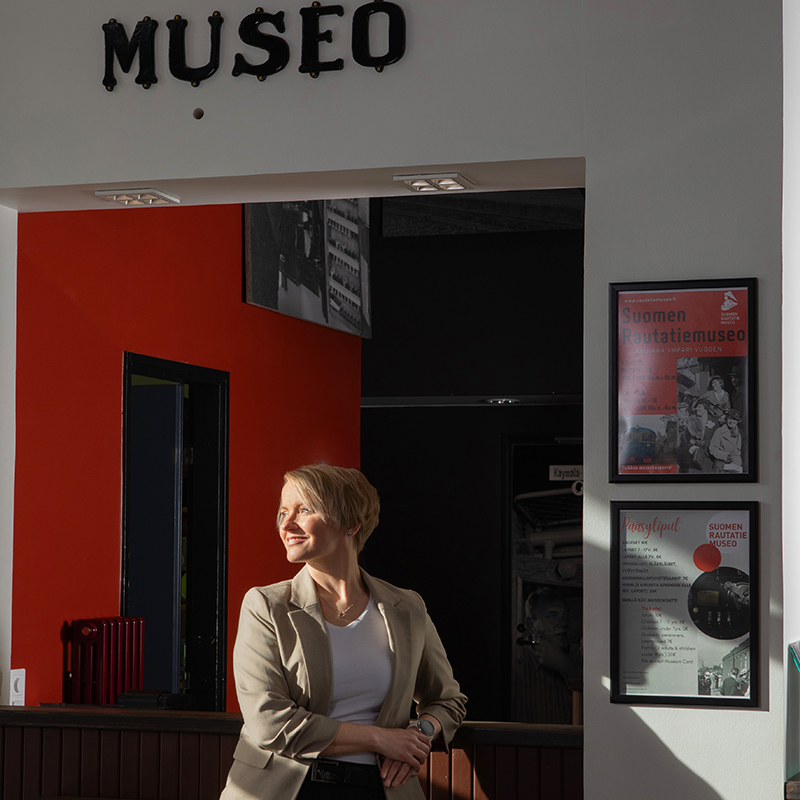 Valeaan pukeutunut henkilö katsoo vinoon kohti valoa. Seinällä teksti"museo".
