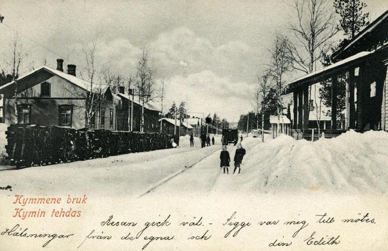 Talvinen rautatieaseman maisema, alaosassa kirjoitusta.