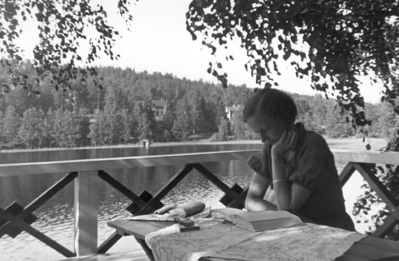 Henkilö lukee kirjaa järven rannalla.